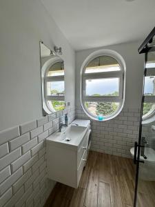 a white bathroom with two windows and a sink at Apartamenty Firfas Rodzinny 11 in Bydgoszcz