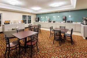 a dining room with tables and chairs and a kitchen at Grandstay Hotel & Suites in Waunakee