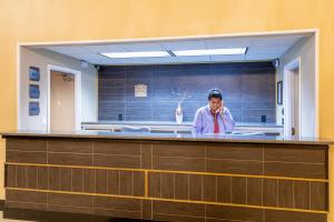 a woman talking on a cell phone behind a counter at Grandstay Hotel & Suites in Waunakee