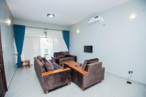 Lubowa View Apartments في كامبالا: غرفة معيشة مع كرسيين وطاولة