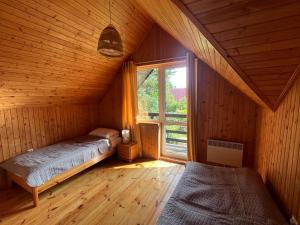 a attic room with two beds and a window at Dom letniskowy nad jeziorem - Kaszuby in Podjazdy