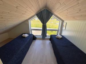 two beds in a room with a window at Mannen Panorama Lofoten in Offersøya