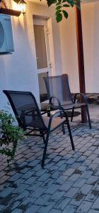 two empty chairs sitting on a brick patio at Seventeen -Apartament la casa in Arad