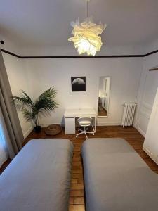 a bedroom with two beds and a desk and a plant at Luxnor Paris in Saint-Ouen