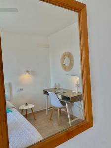 a mirror reflecting a bedroom with a desk and a bed at Apartament Sa Farola - AC, WiFi , Pool, Beach in Cala en Blanes +3 photos
