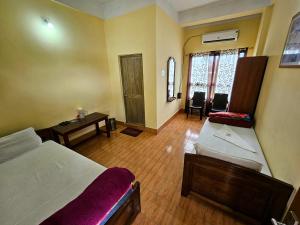 a bedroom with two beds and a table and chairs at Hotel Rishiraj in Jorhāt
