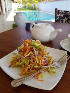 um prato de salada numa mesa com um garfo em Tortuga Beach Hotel em Paiyagala South
