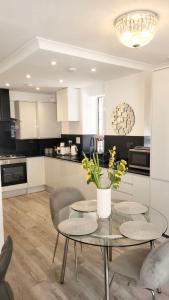 ロンドンにある2 Bedroom Apartment in Regents Parkのガラステーブル、椅子2脚、テーブル付きのキッチンが備わります。
