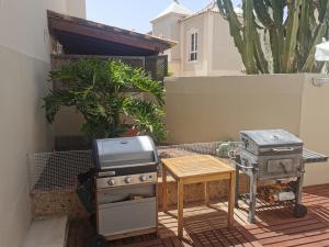 a patio with a grill and a stove and a table at Relax and Enjoy in Tenerife Sud! in Chayofa