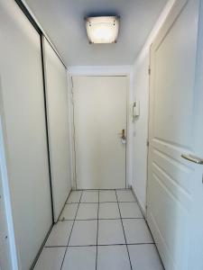 um corredor com uma porta branca e piso em azulejo em Studio Le Pradet em Le Pradet