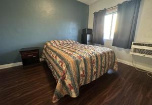 a bedroom with a bed with a blanket and a window at Unity Hotel - No Parking & Rooms Are Upstairs in Long Beach