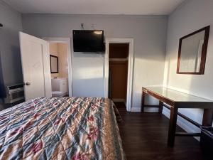 Dormitorio con cama, escritorio y TV en Unity Hotel - No Parking & Rooms Are Upstairs en Long Beach