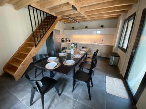 a dining room with a table and chairs and a staircase at Gîte au cœur des Gorges de la Loire in Aurec-sur-Loire