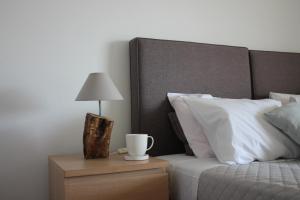 ポルト・ラフティにあるBlue Side Apartment in Porto Raftiのベッド(白い枕付)、テーブル(ランプ付)