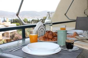un tavolo con piatti di cibo e bicchieri di succo d'arancia di Blue Side Apartment in Porto Rafti a Porto Rafti