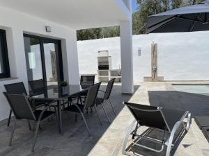 eine Terrasse mit einem Tisch, Stühlen und einem Grill in der Unterkunft Villa La Fuente in Mondrón