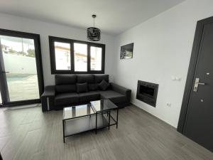 sala de estar con sofá negro y chimenea en Villa La Fuente, en Mondrón