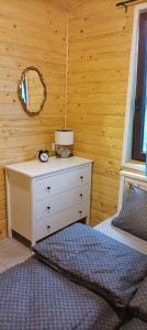 a bedroom with a bed and a dresser and a mirror at Zielenina Leśny Domek in Mierzeszyn