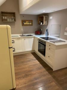 a kitchen with white cabinets and a sink and a refrigerator at The Dairy-Petting Farm-Indoor Pool-Play Areas-Parkland-Woodland-Lake,Ponds&Stream-min2 night stay in Lechlade