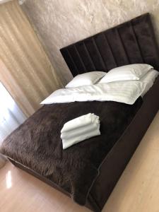Una cama con sábanas blancas y almohadas. en Hotel LION Almaty en Almaty