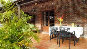 patio con mesa, sillas y pared de ladrillo en Domaine du Château, en Les Trois-Îlets