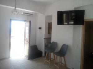 Zimmer mit 3 Stühlen und einem TV an der Wand in der Unterkunft AMPELOS ANDROS in Batsi