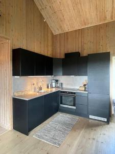 uma cozinha com armários pretos e um tecto de madeira em Leilighet i vakre Rauland em Rauland