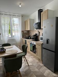 a kitchen with a table and a refrigerator at Bienvenu à l’appart bien-être in Souvigny