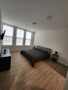 Close to NYC, 10 Guest, Luxurious 3Bedroom Apartment في يونيون سيتي: غرفة نوم بسرير وأرضيات خشبية ونوافذ