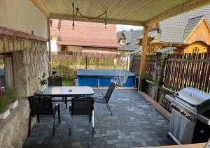 un patio con mesa, sillas y parrilla en Apartament u Jarosza, en Poronin