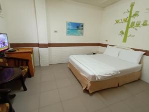 Schlafzimmer mit einem Bett, einem Schreibtisch und einem TV in der Unterkunft Beido Qixing in Beidou