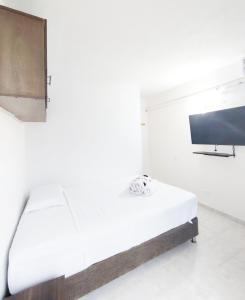 a white bedroom with a bed and a flat screen tv at Apartamentos sophia in San Andrés
