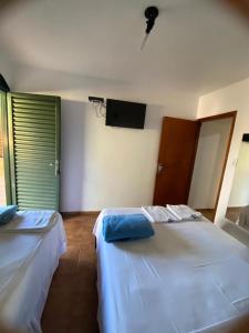 two beds in a room with a tv on the wall at Chalés Holiday House in Rio Quente