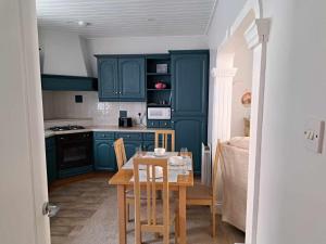 a kitchen with blue cabinets and a table with chairs at Immaculate 2-Bed Cottage - Free WiFi in Bridlington