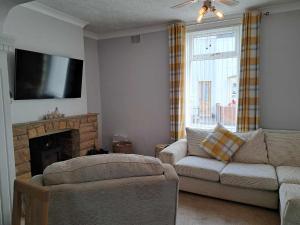 a living room with a couch and a flat screen tv at Immaculate 2-Bed Cottage - Free WiFi in Bridlington
