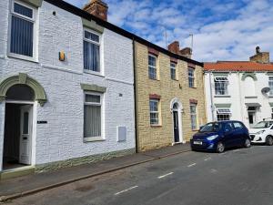 a blue car parked on a street next to buildings at Immaculate 2-Bed Cottage - Free WiFi in Bridlington