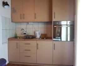 una cocina con armarios de madera y electrodomésticos de acero inoxidable en Studio apartman "DJED" en Hrvatska Kostajnica