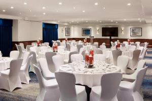 a conference room with white tables and white chairs at London Marriott Hotel Marble Arch in London