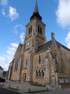 uma velha igreja com uma torre e um relógio nela em Maison de centre ville 6 personnes em Précigné