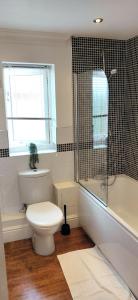 a bathroom with a toilet and a shower and a window at Leamington Spa Warwick Place Apartments in Leamington Spa