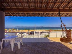 a patio with a table and a view of the beach at Suítes Pé Nareia Itaipuaçu in Maricá