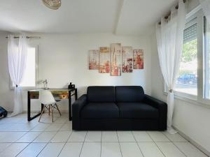um sofá preto numa sala de estar com uma secretária em Studio Le Pradet em Le Pradet
