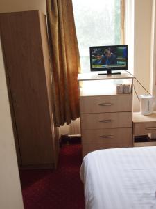 a bedroom with a television on a dresser with a bed at Hotel Olympia in London