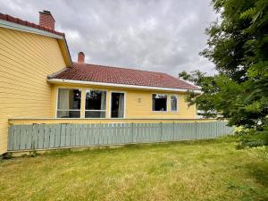 a yellow house with a fence in a yard at Leknes City Apartment in Leknes