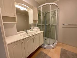 a white bathroom with a shower and a sink at Leknes City Apartment in Leknes