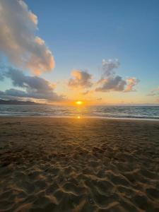 a sunset on a beach with the ocean at Strada-Beach Las Canteras in Las Palmas de Gran Canaria