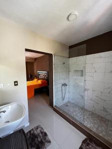uma casa de banho com um chuveiro, um lavatório e uma cama em Casa MIA em Cabarete