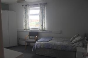 a bedroom with a bed and a chair and a window at Tansterne Grange in Aldbrough