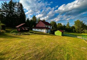 a large grassy field with a house and a barn at Penzion Za potokem in Nová Pec
