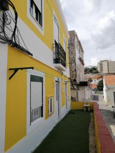un edificio blanco y amarillo con un patio verde en São Philip's House by Casas de Setúbal en Setúbal